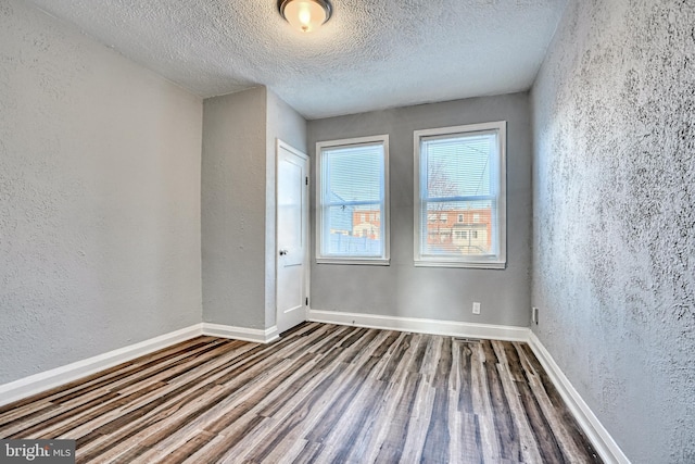 spare room featuring hardwood / wood-style floors and a textured ceiling