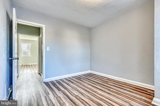 unfurnished room featuring hardwood / wood-style flooring and a textured ceiling