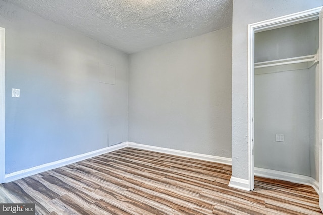 unfurnished bedroom with hardwood / wood-style flooring, a textured ceiling, and a closet