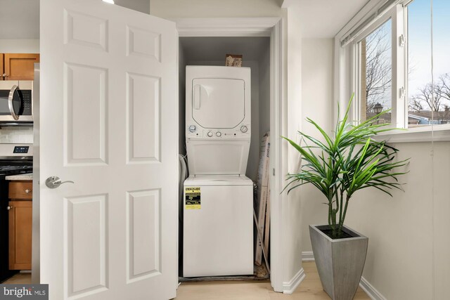 washroom featuring stacked washer / dryer and light hardwood / wood-style floors