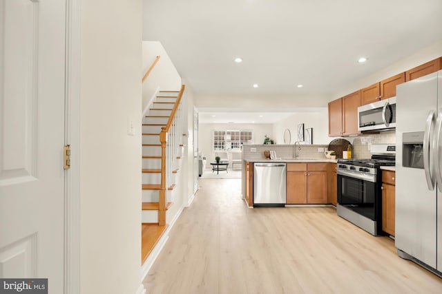 kitchen featuring sink, decorative backsplash, light wood-type flooring, and appliances with stainless steel finishes