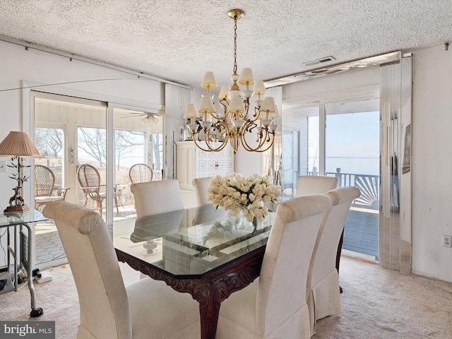 dining room featuring light carpet, visible vents, a chandelier, and a textured ceiling