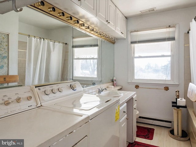 washroom with a baseboard heating unit, washer and dryer, laundry area, and visible vents