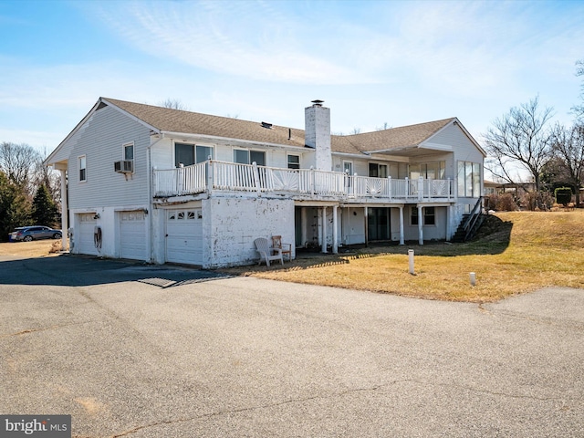 view of front of property featuring a garage, a chimney, a front lawn, and aphalt driveway