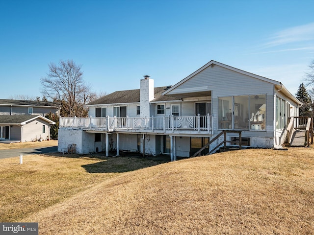 view of front of property with a sunroom, a chimney, stairway, a wooden deck, and a front lawn