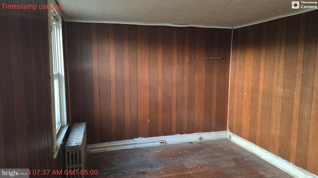 unfurnished room featuring wooden walls