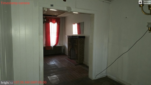 hall with radiator heating unit and dark hardwood / wood-style flooring