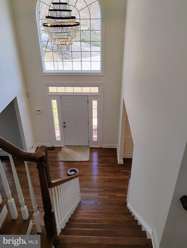 entrance foyer featuring stairs, an inviting chandelier, wood finished floors, and a towering ceiling