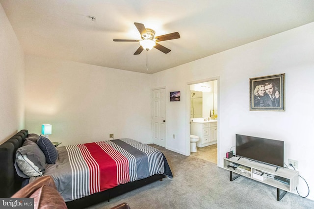 bedroom featuring ceiling fan, light colored carpet, and connected bathroom