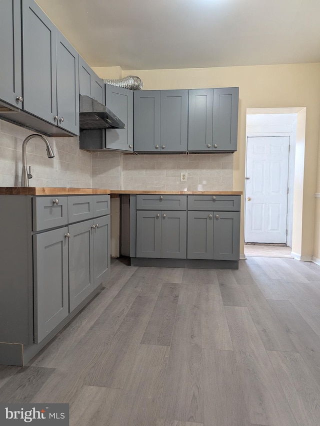 kitchen featuring gray cabinetry, light hardwood / wood-style floors, and decorative backsplash