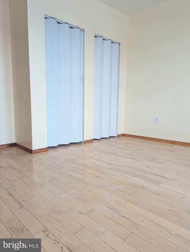 unfurnished bedroom featuring two closets and light hardwood / wood-style flooring