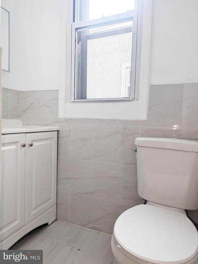 bathroom featuring vanity, tile walls, and toilet