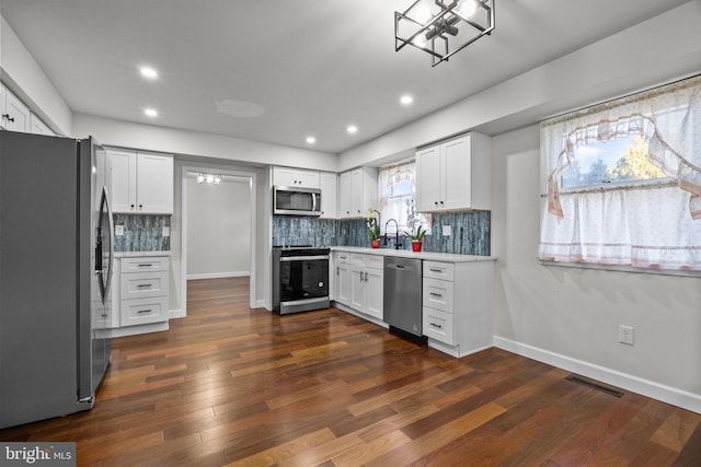 kitchen with stainless steel appliances, white cabinetry, dark wood-type flooring, and tasteful backsplash