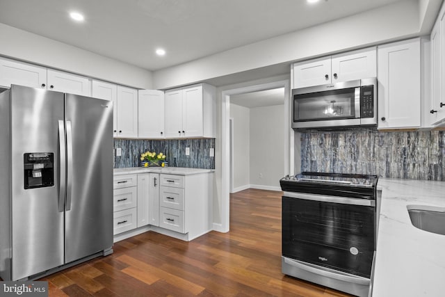 kitchen featuring backsplash, white cabinets, dark hardwood / wood-style flooring, stainless steel appliances, and light stone countertops