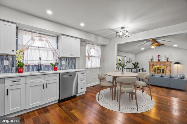 kitchen with white cabinetry, sink, stainless steel dishwasher, and a fireplace