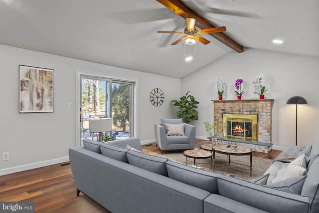 living room with ceiling fan, hardwood / wood-style floors, a brick fireplace, and vaulted ceiling with beams