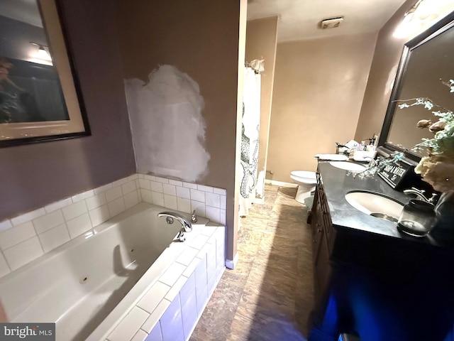 bathroom featuring vanity, toilet, and tiled tub