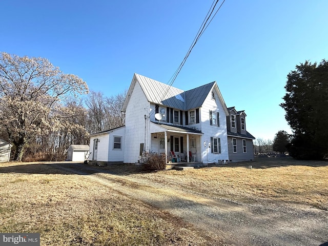 view of front facade with a garage, an outdoor structure, a front yard, and covered porch