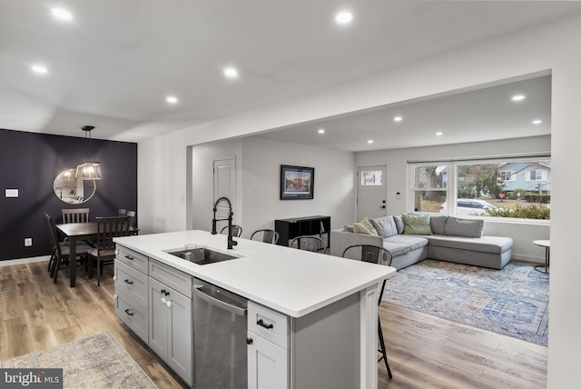 kitchen with hardwood / wood-style flooring, a kitchen island with sink, dishwasher, and sink