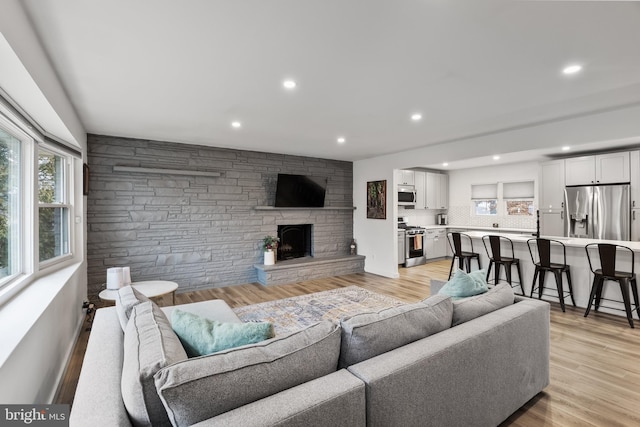 living room featuring a stone fireplace and light wood-type flooring