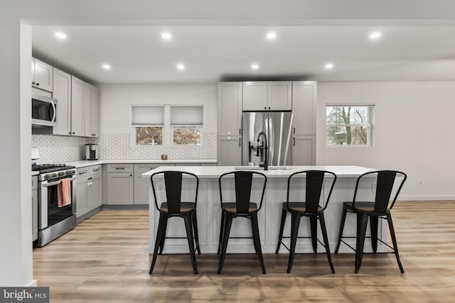 kitchen with appliances with stainless steel finishes, a center island, a kitchen bar, and light wood-type flooring