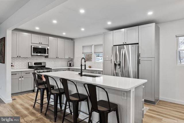 kitchen featuring stainless steel appliances, a kitchen island with sink, sink, and a breakfast bar area