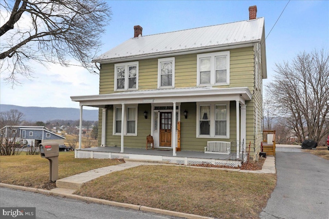 view of front of property with a mountain view, a front lawn, and a porch