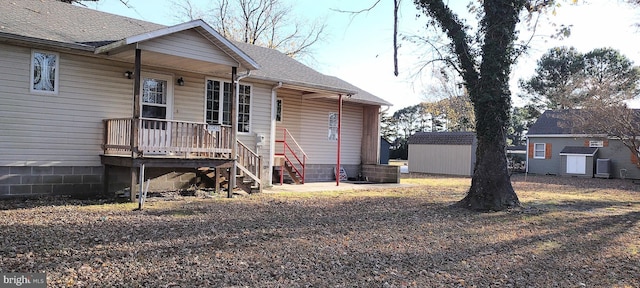 back of house with a storage unit