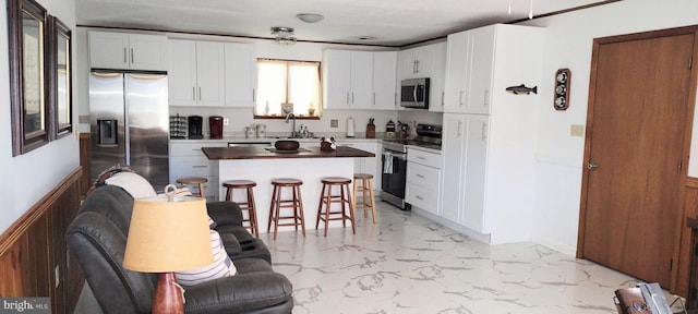 kitchen featuring sink, a center island, a kitchen breakfast bar, stainless steel appliances, and white cabinets