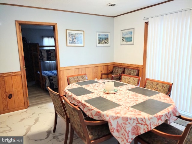 dining space featuring ornamental molding and wood walls