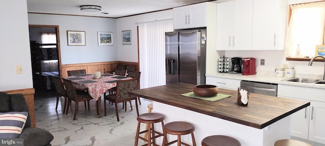 kitchen featuring white cabinetry, wood counters, stainless steel appliances, and sink