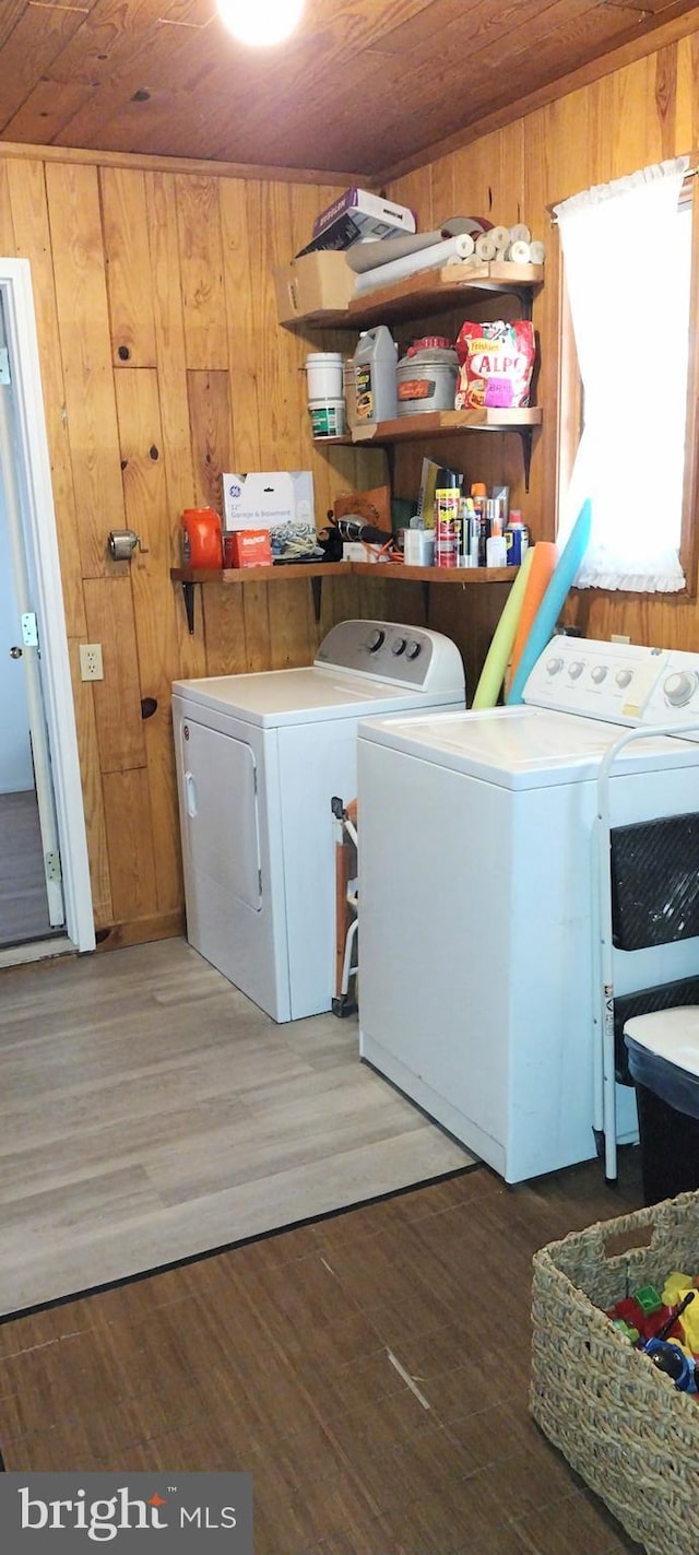 washroom with wood ceiling, washer and clothes dryer, dark wood-type flooring, and wood walls