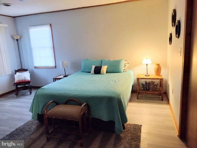 bedroom with hardwood / wood-style floors and crown molding