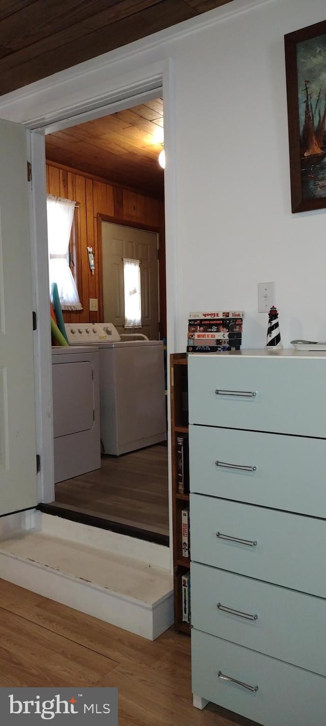 interior space with hardwood / wood-style flooring, wooden walls, and washer and dryer