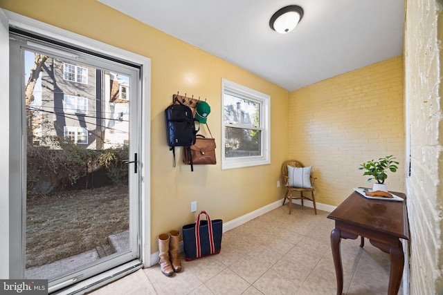 doorway with light tile patterned flooring and brick wall