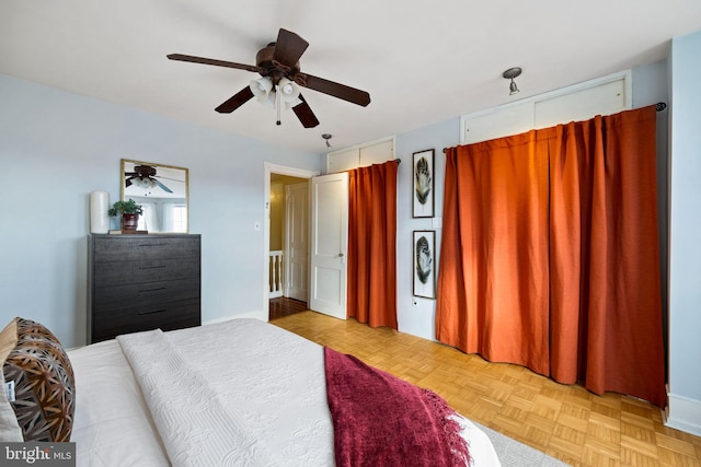 bedroom featuring ceiling fan, multiple closets, and light parquet flooring