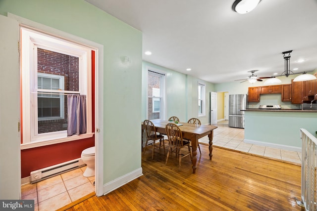 dining area featuring a baseboard heating unit, ceiling fan, and light hardwood / wood-style flooring