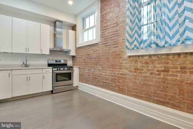 kitchen with white cabinets, stainless steel range with gas cooktop, sink, and wall chimney exhaust hood