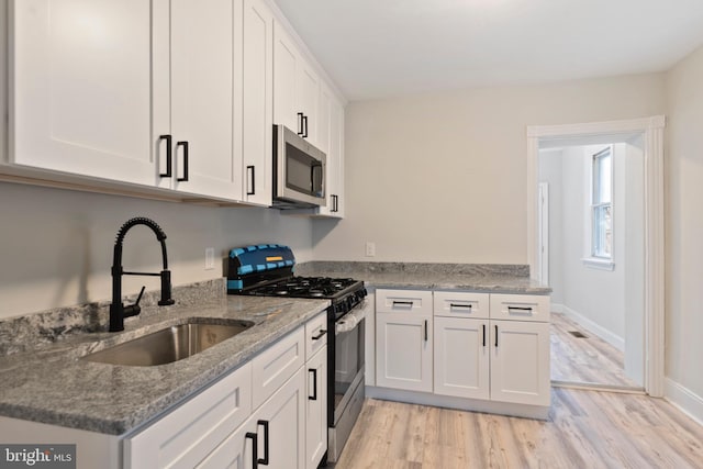 kitchen with white cabinetry, appliances with stainless steel finishes, sink, and light stone counters