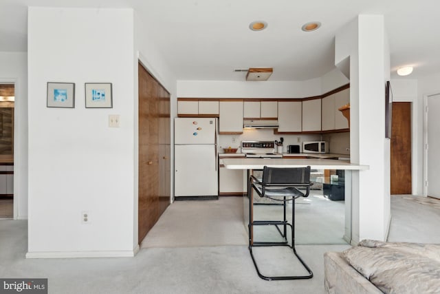 kitchen featuring a breakfast bar area, white appliances, and kitchen peninsula