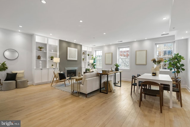 living room with built in features and light hardwood / wood-style flooring