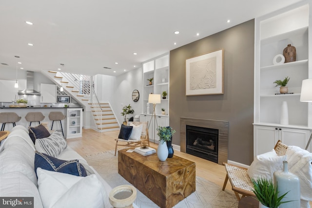 living room with built in features and light hardwood / wood-style floors