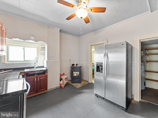 kitchen featuring sink, water heater, stainless steel refrigerator with ice dispenser, ornamental molding, and a wood stove