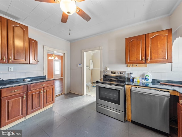 kitchen with tile patterned floors, crown molding, ceiling fan, stainless steel appliances, and decorative backsplash