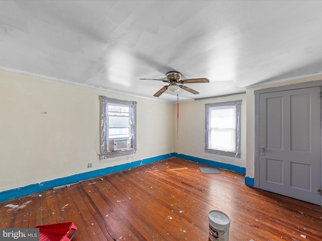 empty room featuring hardwood / wood-style flooring, a healthy amount of sunlight, cooling unit, and ceiling fan