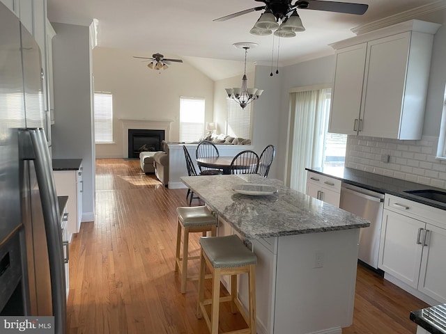 kitchen featuring a breakfast bar, appliances with stainless steel finishes, a kitchen island, light hardwood / wood-style floors, and white cabinets