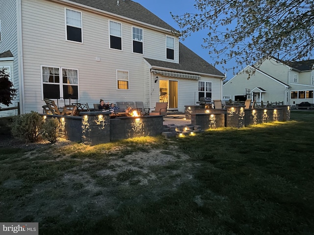 rear view of house featuring a lawn, a patio, and an outdoor fire pit