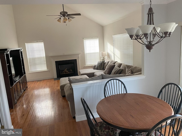 dining area featuring ceiling fan with notable chandelier, light hardwood / wood-style flooring, and high vaulted ceiling