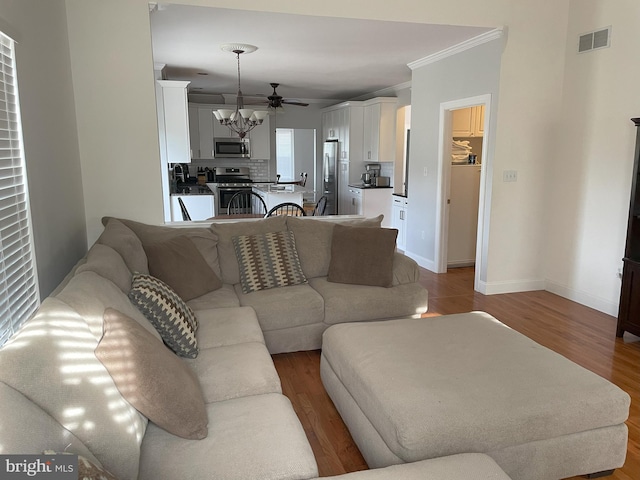 living room featuring ornamental molding, an inviting chandelier, and light hardwood / wood-style flooring