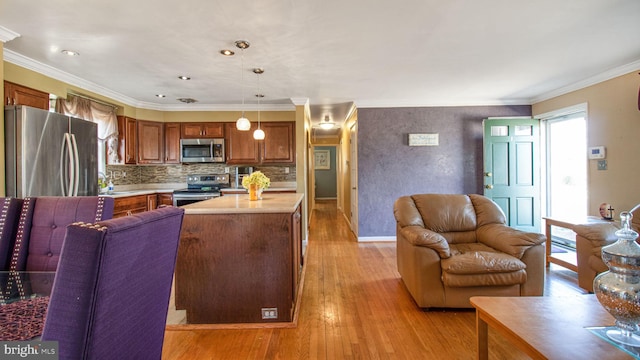 kitchen featuring crown molding, stainless steel appliances, decorative light fixtures, and light hardwood / wood-style floors